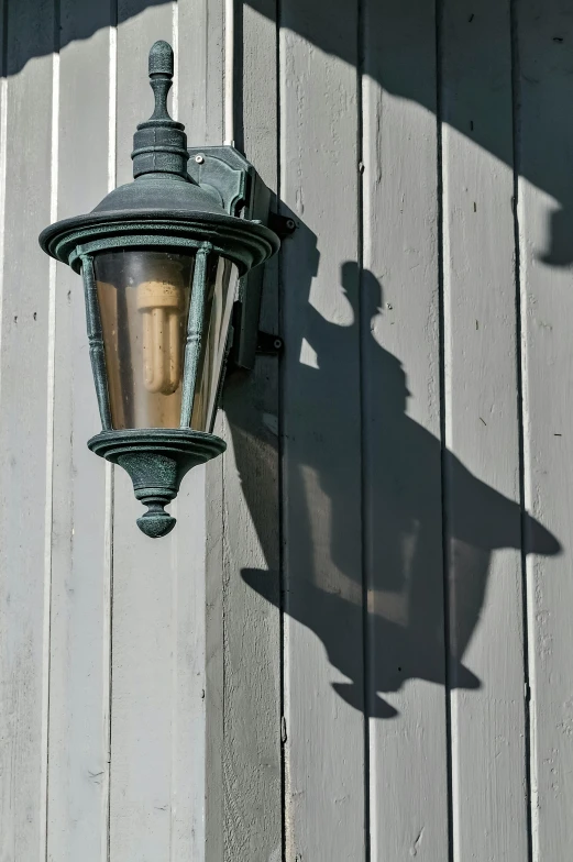 a light that is on the side of a building, by David Simpson, contrasting shadows, carbide lamp, patina, cottage close up