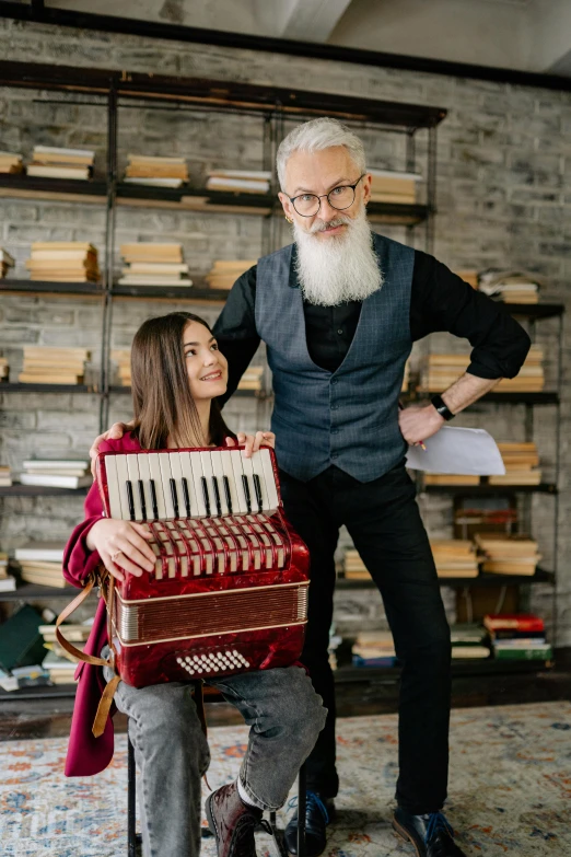 a man standing next to a woman holding an accordion, pexels contest winner, long grey beard, nerdy music teacher with phd, standing on top of a piano, little kid