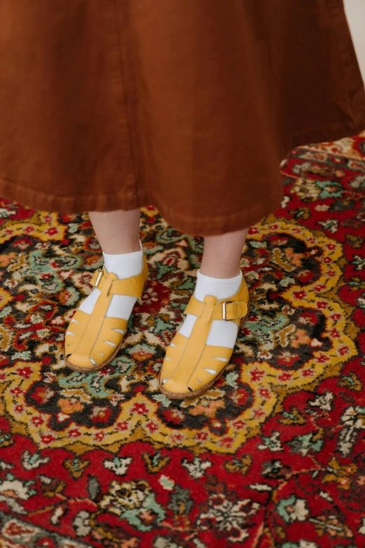 a person standing on a rug wearing yellow shoes, inspired by Modest Urgell, clogs, wearing a toga and sandals, (((yellow))), girls