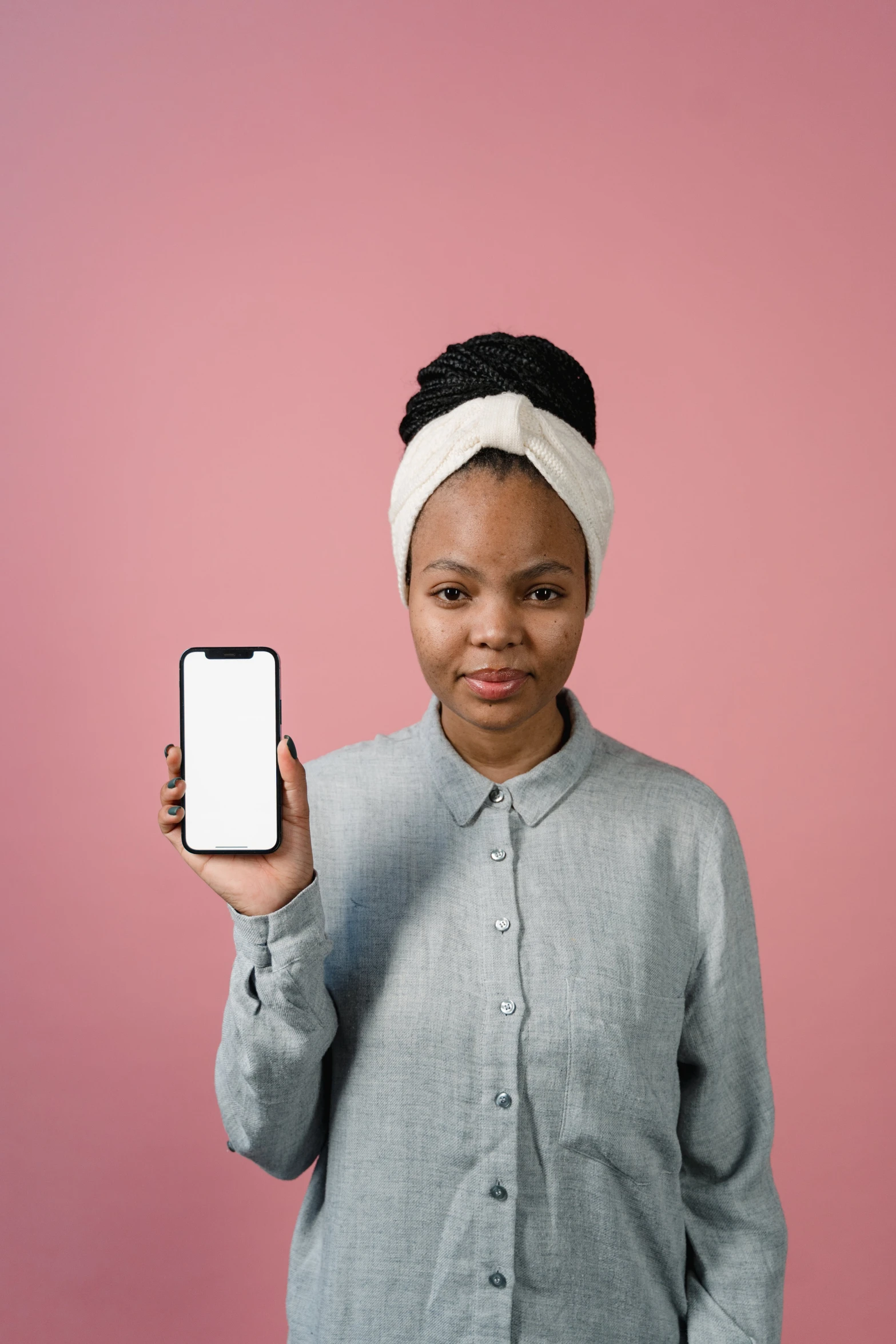 a close up of a person holding a cell phone, a picture, trending on pexels, afrofuturism, blank expression on her face, plain background, pink skin, casually dressed