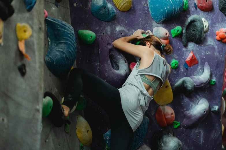 a woman is climbing on a rock wall, pexels contest winner, graffiti, 🦩🪐🐞👩🏻🦳, indoor scene, top down, resting