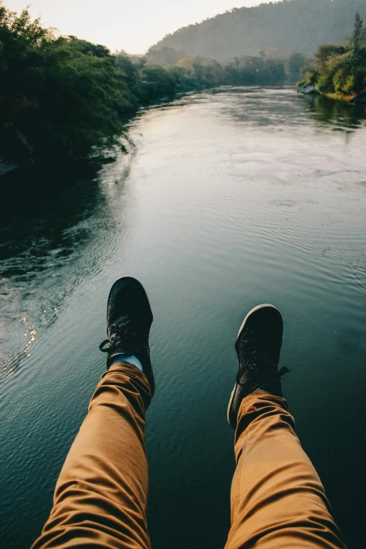 a person sitting on the edge of a body of water, trending on unsplash, happening, legs taking your pov, river rapids, duck shoes, really long