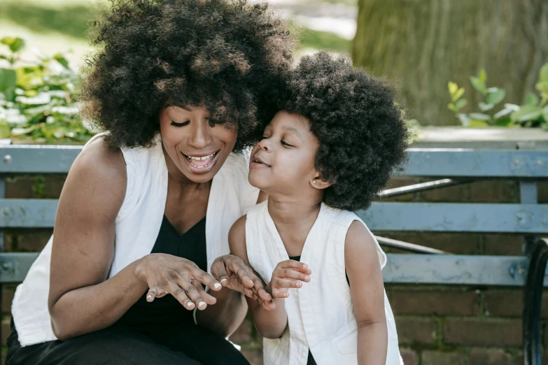 a woman sitting next to a little girl on a bench, by Lily Delissa Joseph, pexels contest winner, afro comb, having fun, avatar image, sleek hands