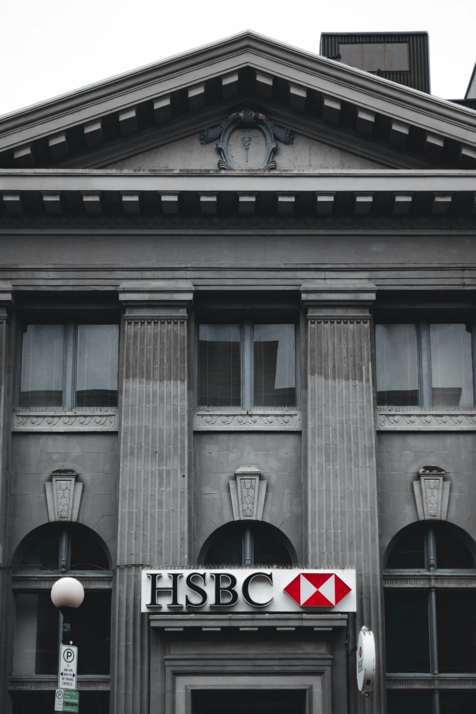 a black and white photo of a building with a hsbc sign, a colorized photo, pexels contest winner, portrait photo, bank, trending on vsco, on a great neoclassical square