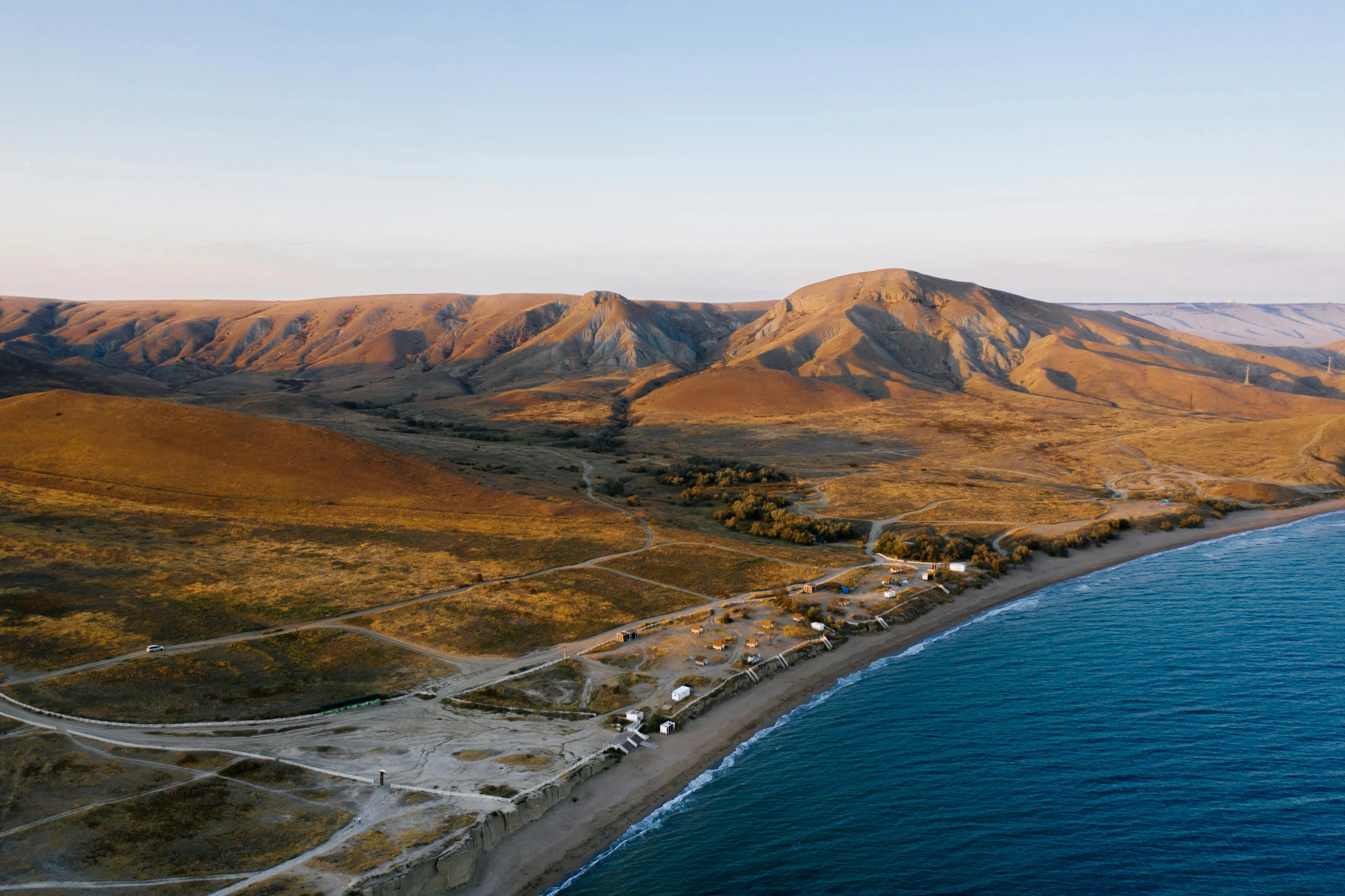 an aerial view of a beach with mountains in the background, hurufiyya, glamping, research station, conde nast traveler photo