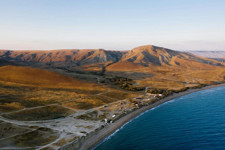 an aerial view of a beach with mountains in the background, hurufiyya, glamping, research station, conde nast traveler photo