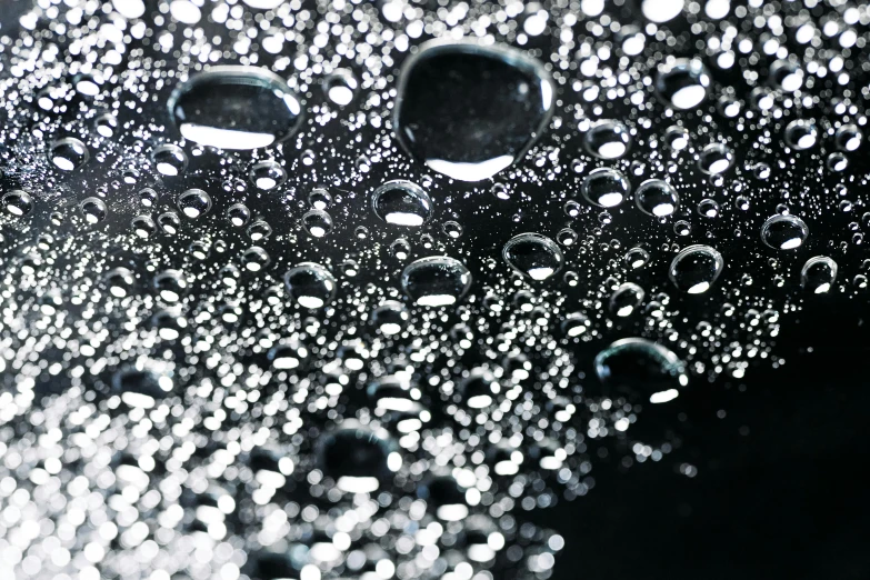 a close up of water droplets on a surface, a stipple, by David Donaldson, unsplash, photorealism, bubbly underwater scenery, on black paper, shiny materials, translucent orbs