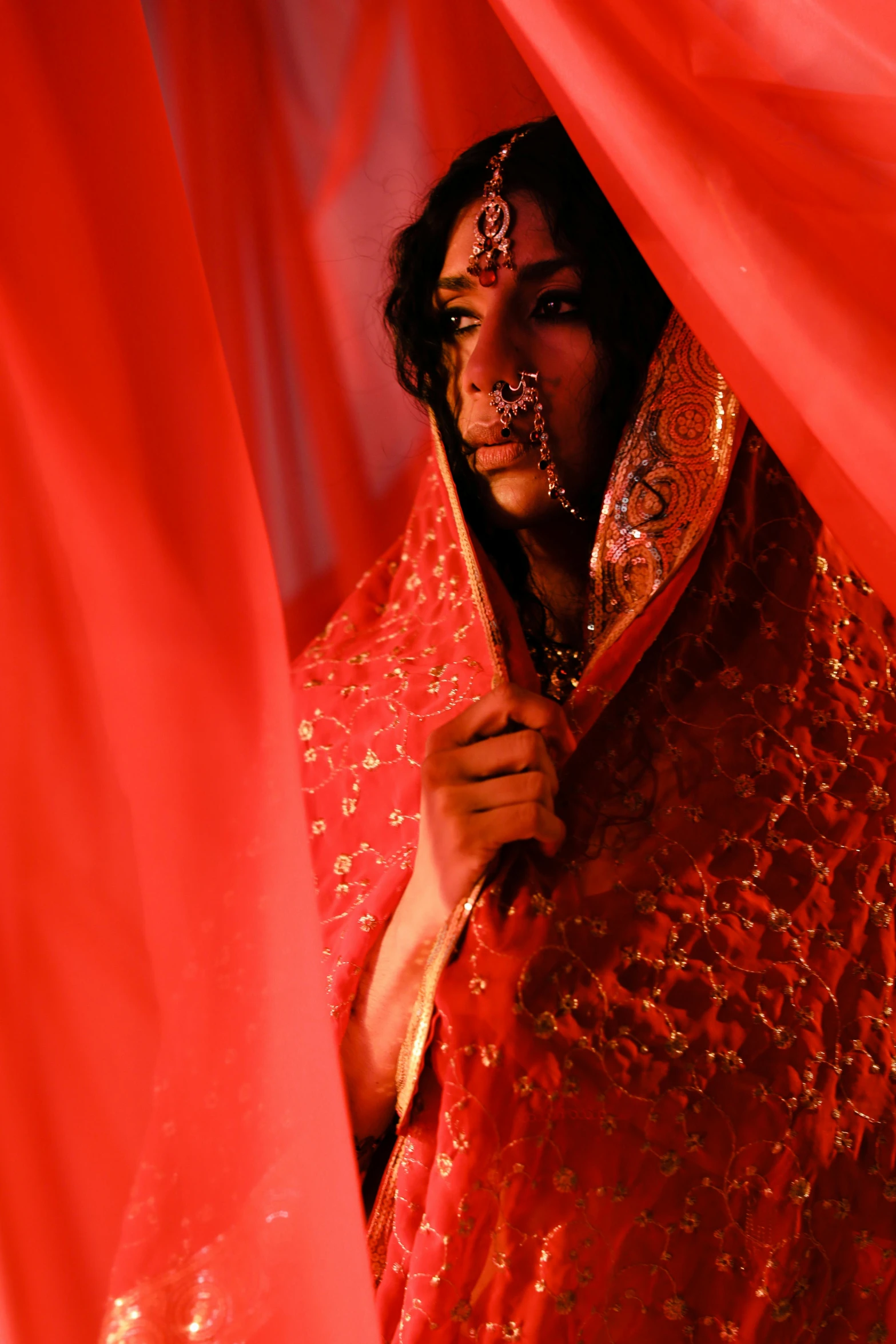 a woman is hiding behind a red curtain, an album cover, flickr, transgressive art, dressed in a sari, holy ceremony, pride, photographed for reuters