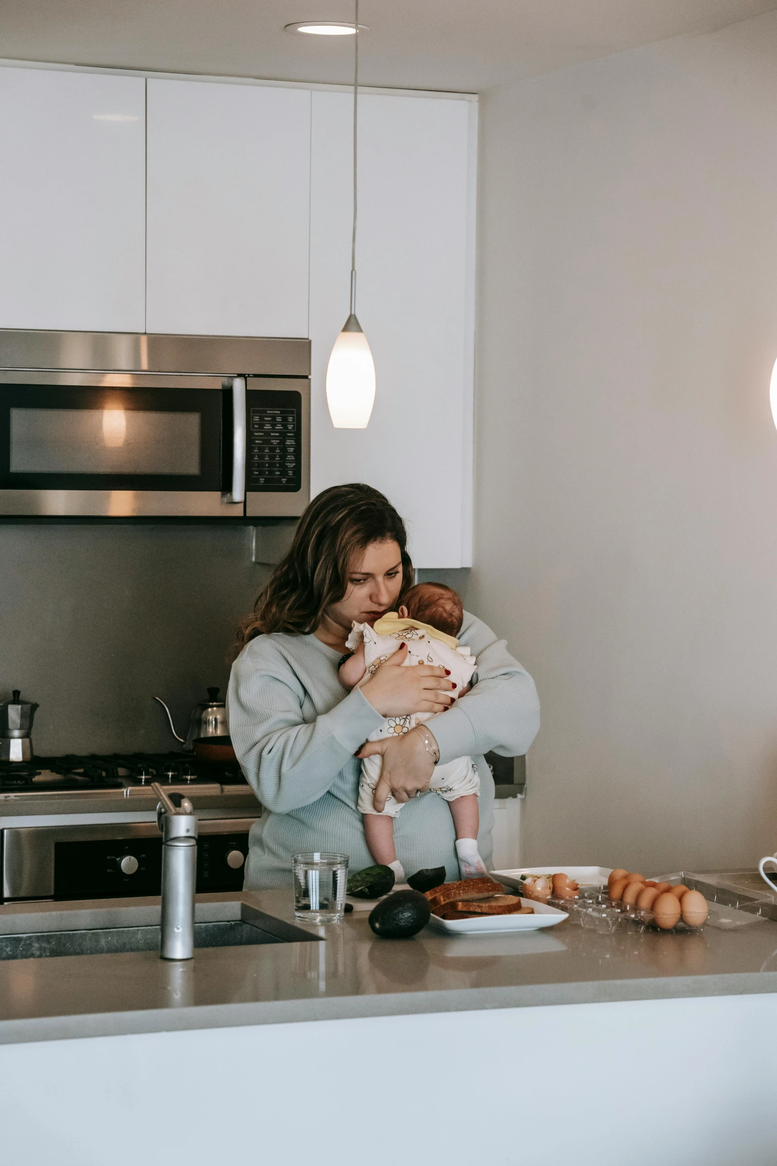 a woman holding a baby in a kitchen, trending on reddit, beautifully soft lit, brunette, breakfast, high quality photo