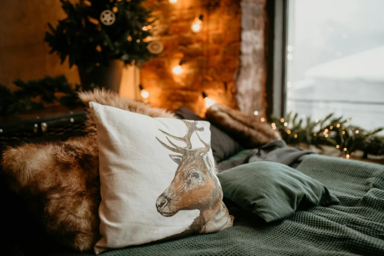 a pillow sitting on top of a bed next to a window, a portrait, inspired by Ernest William Christmas, pexels contest winner, deer, cosy fireplace, full product shot, tattooed