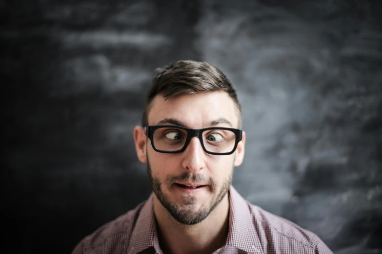 a man with glasses standing in front of a blackboard, pexels contest winner, manly face, josh black, square rimmed glasses, surprised