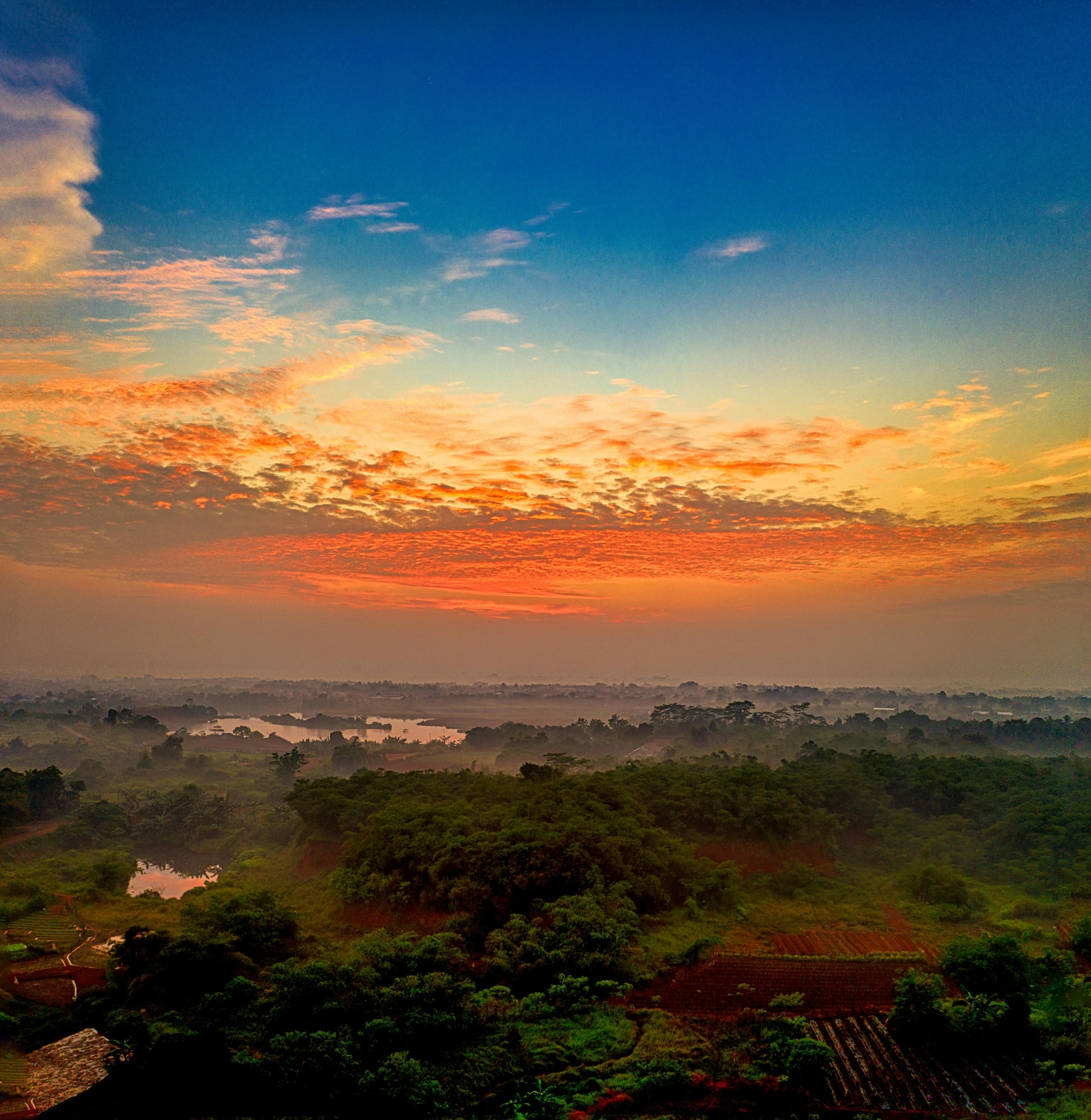 a large body of water surrounded by trees, by Sudip Roy, pexels contest winner, sunrise colors, distant villagescape, panorama view of the sky, high view