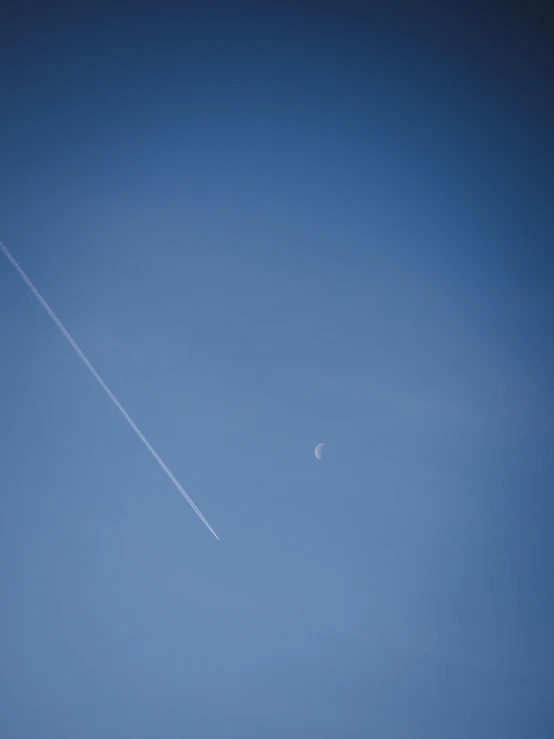 a person is flying a kite in the sky, by Niko Henrichon, postminimalism, international space station, waning moon, contrails, blue