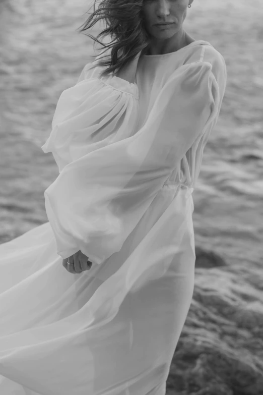 a black and white photo of a woman in a white dress, inspired by Max Dupain, unsplash, renaissance, on the ocean water, soft silk dress, detail, white sleeves