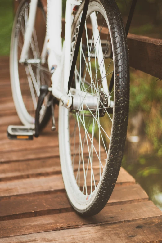 a white bicycle parked on a wooden bridge, gum rubber outsole, digital image, full width, wheel