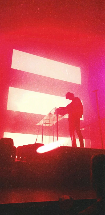 a man standing on top of a stage in front of a red light, synthetism, washed out colors, synth feel, instagram picture, official screenshot