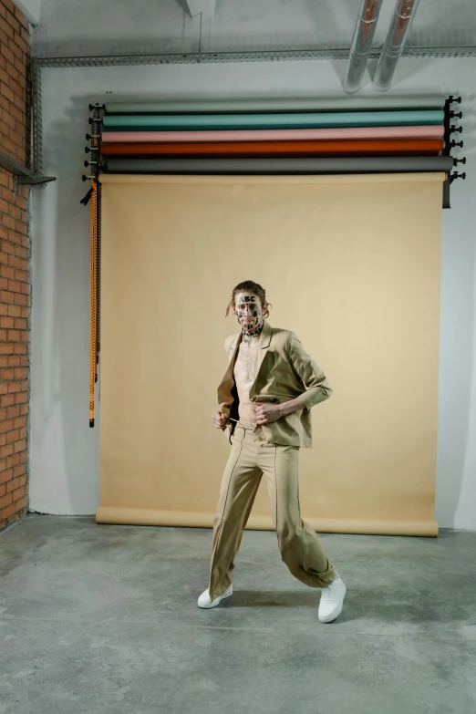 a woman in a tan suit and white sneakers, by Nina Hamnett, trending on pexels, bauhaus, studio backdrop, nonbinary model, lunging at camera :4, travis scott