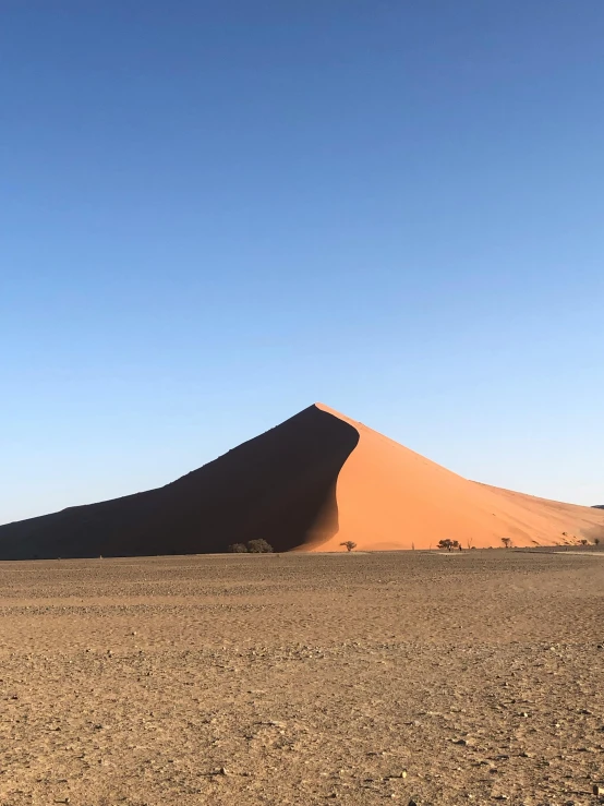 a large sand dune in the middle of a desert, by Terese Nielsen, red dust, side view from afar, 1km tall, gravels around