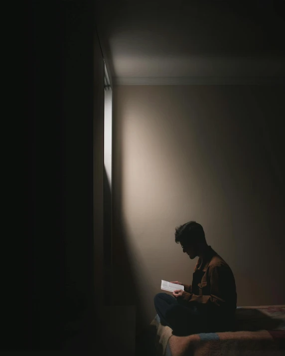 a man sitting on a bed reading a book, light and space, dark ominous mood, bisexual lighting, instagram story, writing a letter