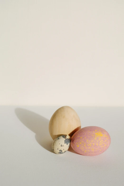 three eggs sitting next to each other on a table, unsplash, folk art, pink and yellow, ignant, cedar, liang mark