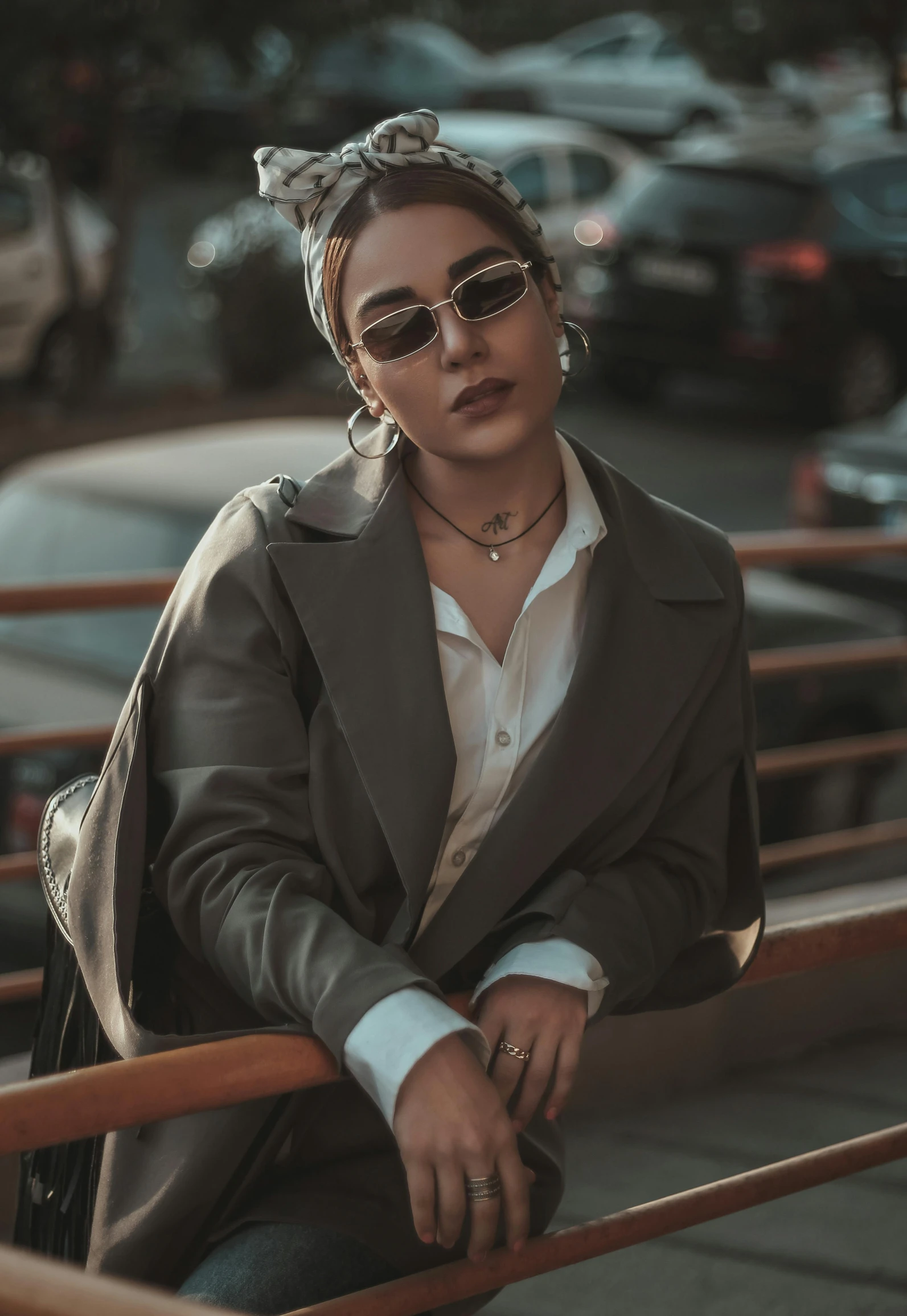 a woman sitting on a bench in a parking lot, inspired by Elsa Bleda, trending on pexels, renaissance, wearing a suit and glasses, cropped shirt with jacket, anna nikonova aka newmilky, trending on artstion