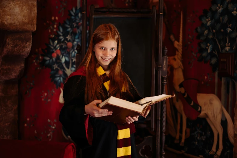 a girl in a harry potter costume holding a book, inspired by Hermione Hammond, private press, hogwarts gryffindor common room, medium-shot, for junior, robes