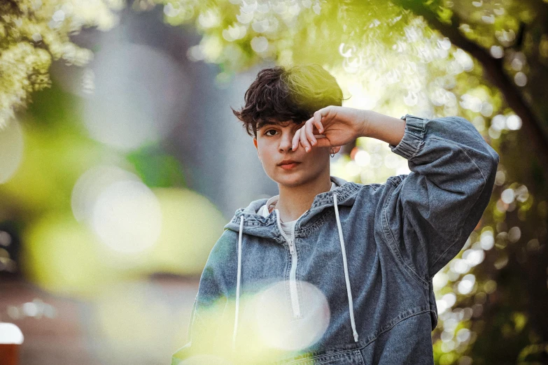 a close up of a person wearing a hoodie, inspired by John Luke, trending on pexels, beautiful androgynous prince, amongst foliage, wearing casual clothes, posing for a picture