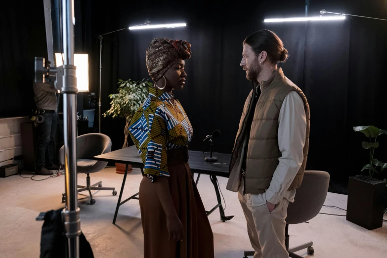 a man standing next to a woman in a room, wakanda, on set, epk, wearing an african dress