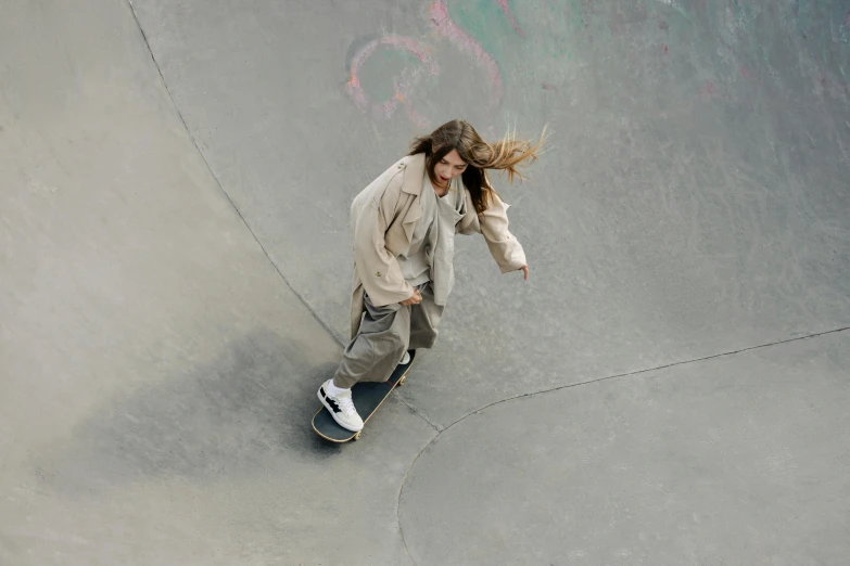 a man riding a skateboard up the side of a ramp, trending on pexels, her hair flowing down, on grey background, aerial shot, off - white collection