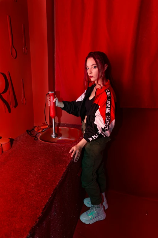 a woman standing in front of a red neon sign, an album cover, trending on pexels, antipodeans, drinking, better known as amouranth, wearing a track suit, standing in corner of room