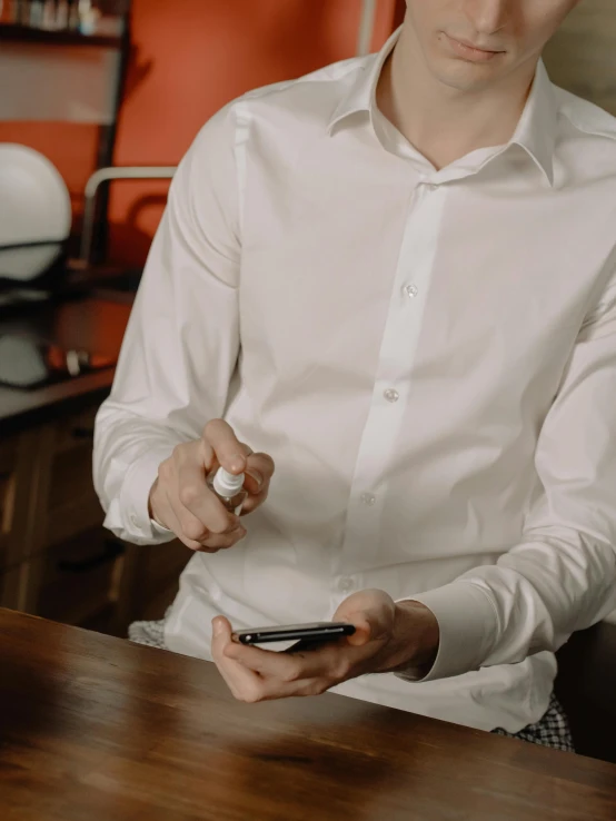 a man sitting at a table holding a cell phone, white dress shirt, thumbnail, taken in 2 0 2 0, tight shirt