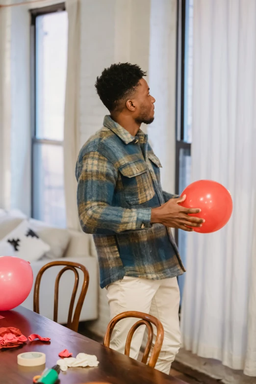 a man standing in a living room holding a balloon, wearing a flannel shirt, playing, hypersphere, profile image