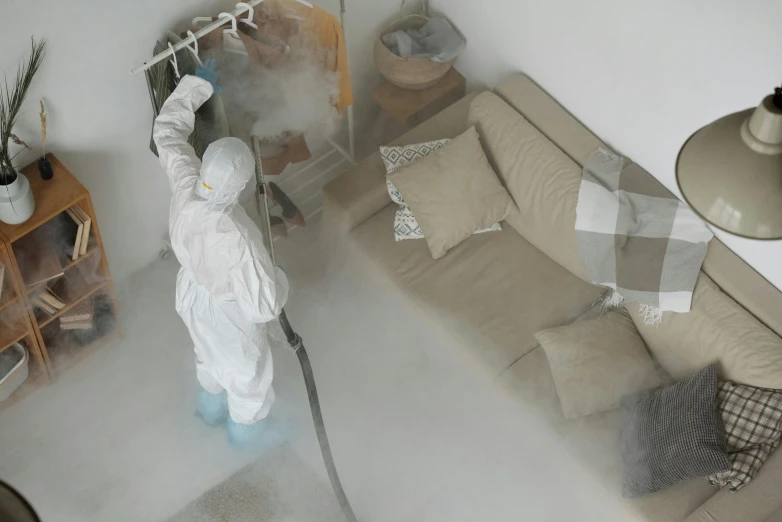 a person in a white suit sprays a couch, wide aerial shot, healthcare worker, profile image, dirty linen robes