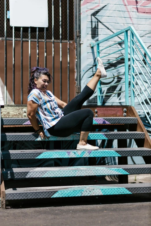 a woman sitting on the steps of a building, breakdancing, non-binary, wearing fitness gear, standing astride a gate