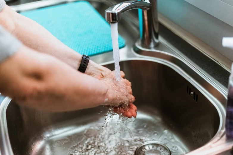 a person washing their hands in a sink, by Daniel Lieske, pexels contest winner, fan favorite, stainless steel, hydration, nursing