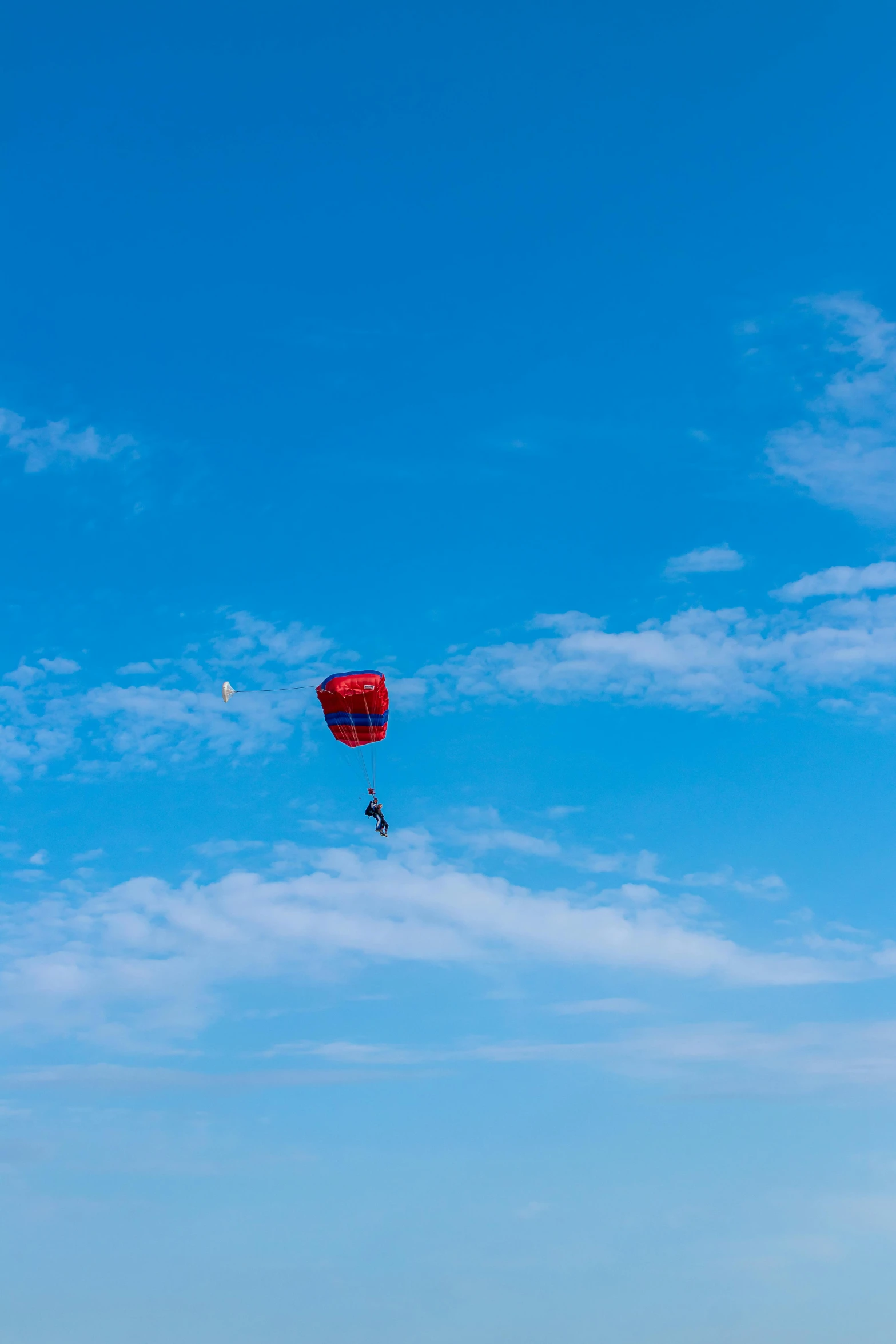 a person on a beach flying a kite, auckland sky tower, d. b. cooper skydiving, blue and red color scheme, taken in 2 0 2 0