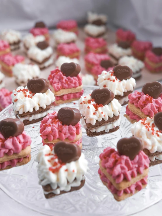 a plate of cupcakes with white frosting and pink sprinkles, by Lilia Alvarado, pexels, happening, (heart), marshmallow graham cracker, highly detailed in 4k”, chocolate candy bar packaging