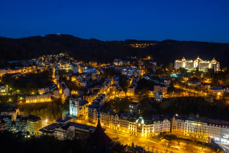 an aerial view of a city at night, by Julia Pishtar, pexels contest winner, art nouveau, black forest, square, city on a hillside, blue