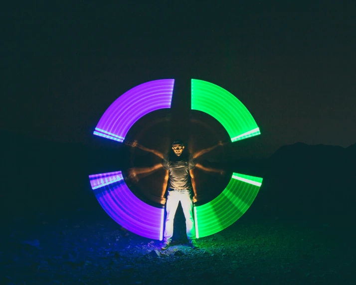 a man standing in front of a circular light painting, pexels contest winner, kinetic art, triadic color grading, outdoor rave, rim lights purple and green, instagram picture