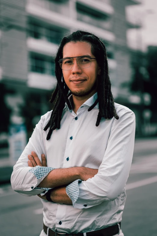 a man standing on a street with his arms crossed, by Alejandro Obregón, reddit, young with long hair, on clear background, professional profile photo, colombian