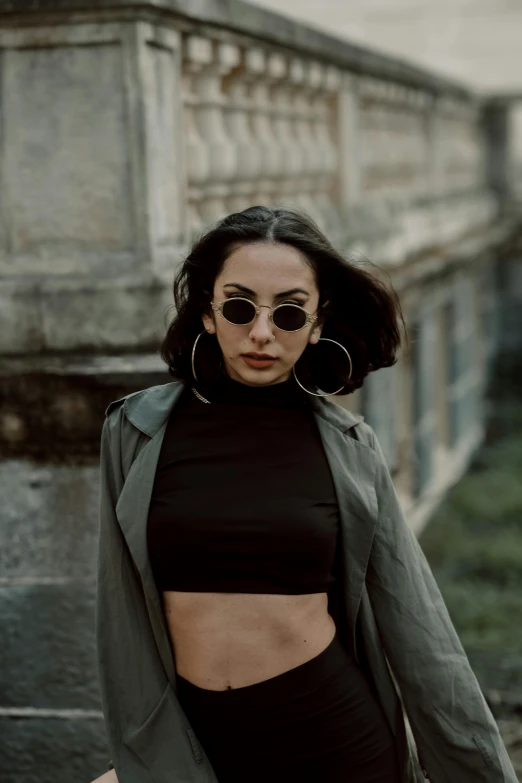 a woman in a black top and a green jacket, pexels contest winner, croptop, circular sunglasses, 5 0 0 px models, black in