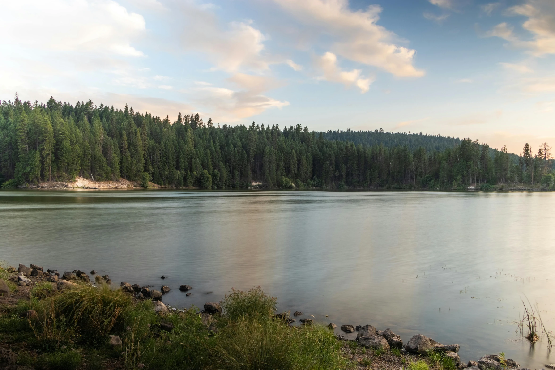 a large body of water next to a forest, by Jessie Algie, unsplash, central california, fan favorite, red lake, evening time