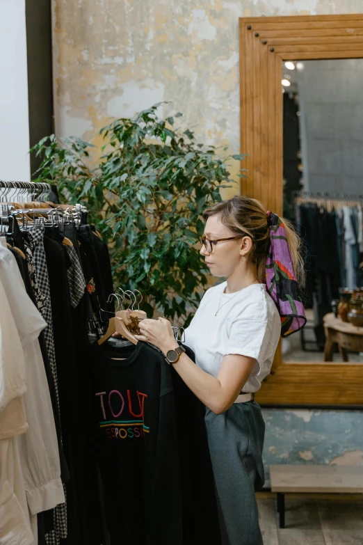 a woman standing in front of a rack of clothes, inspect in inventory image, indi creates, gif, tourist photo