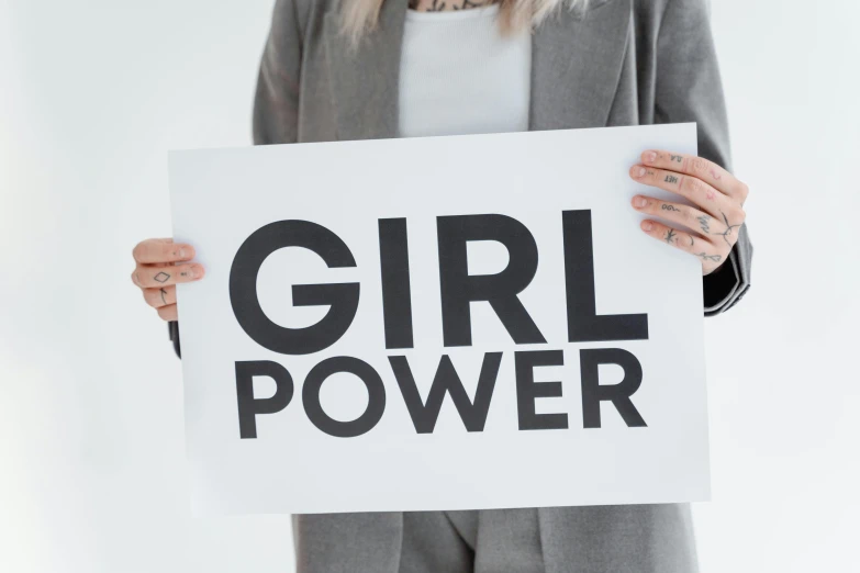 a woman holding a sign that says girl power, a poster, inspired by Harriet Powers, trending on pexels, grey, circuit, product shot, amanda lilleston