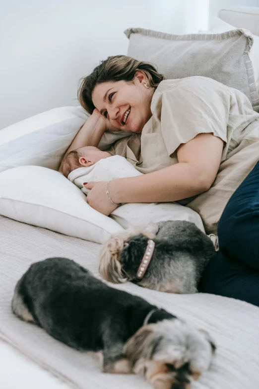 a woman laying on a bed with two dogs, pexels contest winner, babies in her lap, australian, profile image, maternity feeling