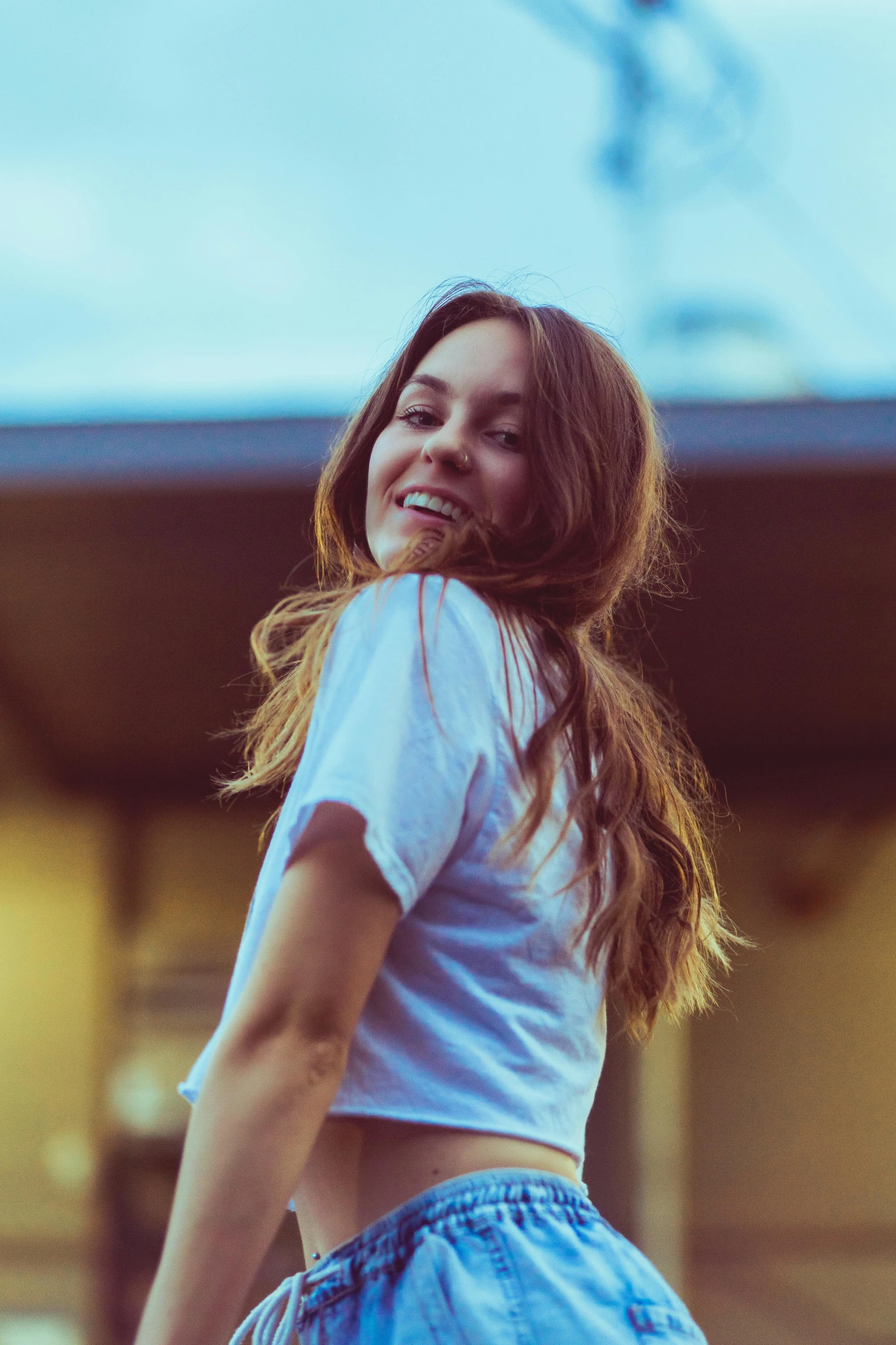 a beautiful young woman standing in front of a building, pexels contest winner, happening, dressed in a white t-shirt, madly grinning, girl with dark brown hair, pokimane