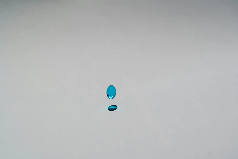 a blue object sitting on top of a white surface, drops are falling from above, f / 1. 9 6. 8 1 mm iso 4 0, turqouise, very tiny