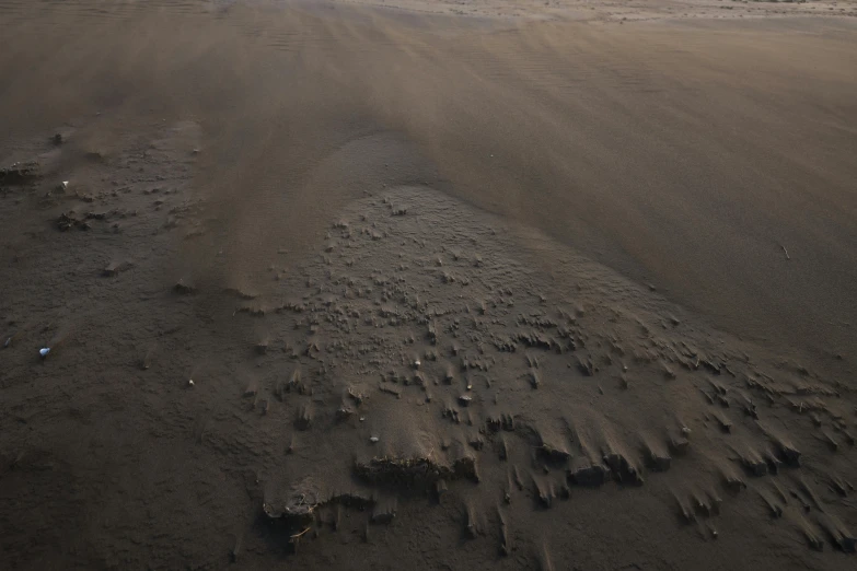 a man riding a surfboard on top of a sandy beach, a detailed matte painting, by Daniel Lieske, pexels contest winner, lots of mud puddles and craters, taken from a plane, volumetric dust, close - up photograph