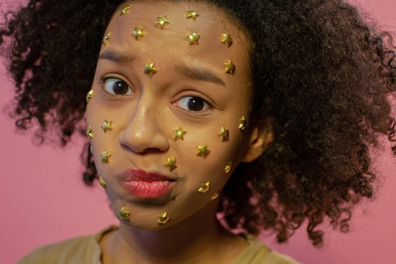 a girl with gold stars on her face, trending on pexels, afrofuturism, rebecca sugar, flushed face, toy commercial photo, gen z