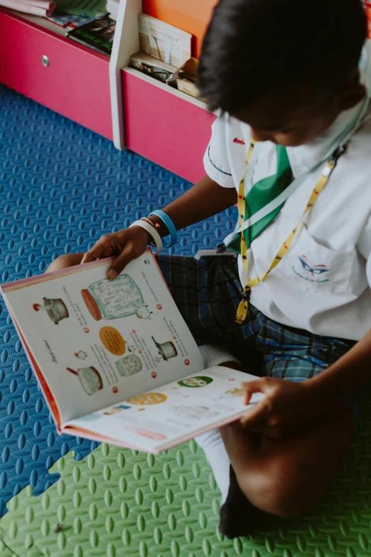 a boy sitting on the floor reading a book, a cartoon, pexels contest winner, quito school, girl wearing uniform, thailand, roleplay, a brightly coloured